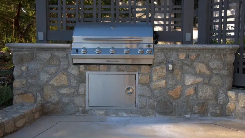 Stone outdoor kitchen with a built in grill and a stone counter