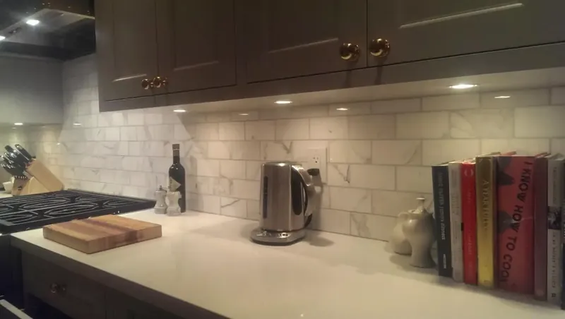 Marble subway tile backsplash under dark kitchen cabinets