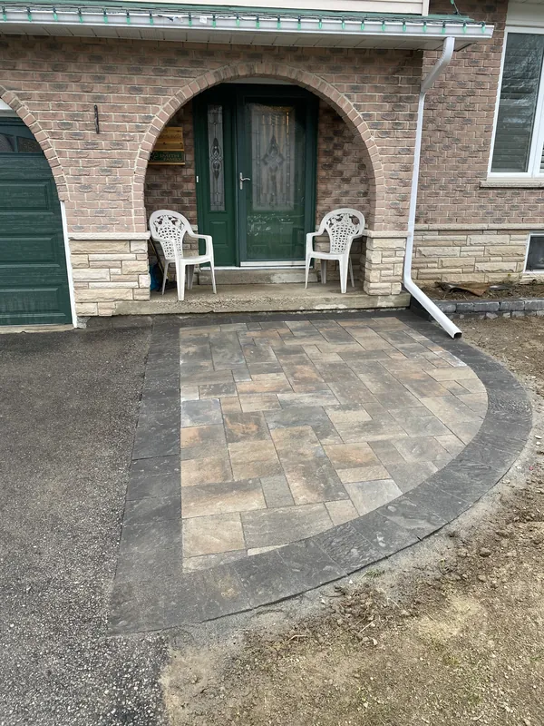 Curved paver walkway with a dark border at an arched brick front entry