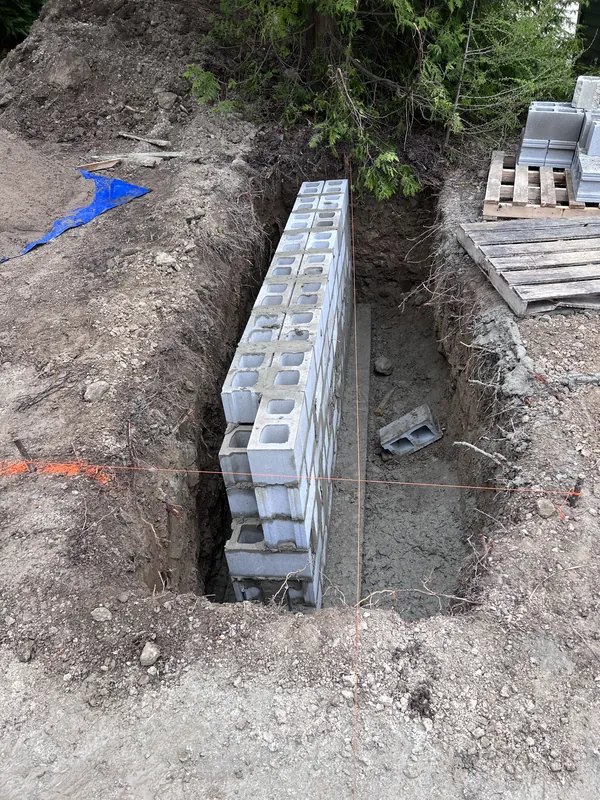 Concrete block wall rising from the footing of a dug trench