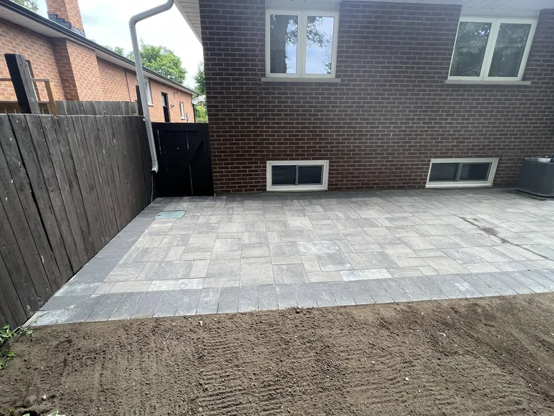 Paver patio with a contrasting border behind a brick house
