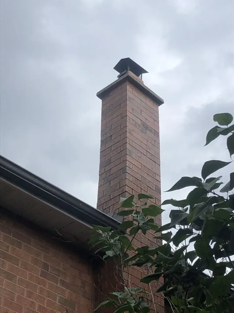 Rebuilt red brick chimney against an open sky
