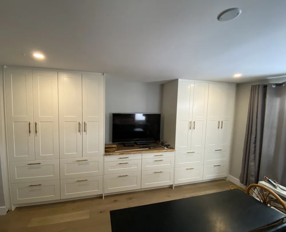 White built-in wall unit of custom cabinets and drawers with brass pulls
