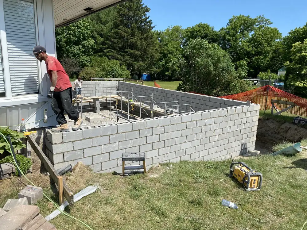 Crew laying a concrete block foundation wall on a new residential build